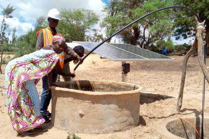 A few people drawing water from a well.