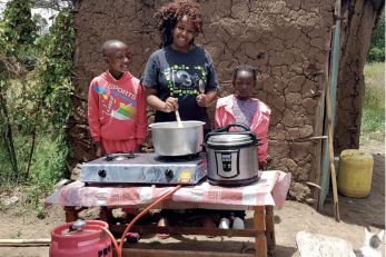 woman and two children at table with cooking pot