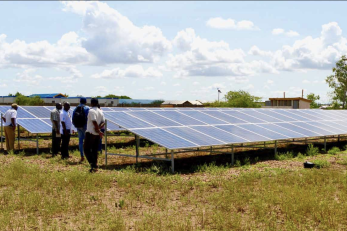 group of adults standing near solar panels