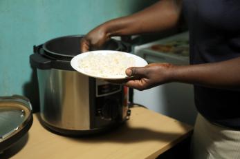 person scooping food from pot